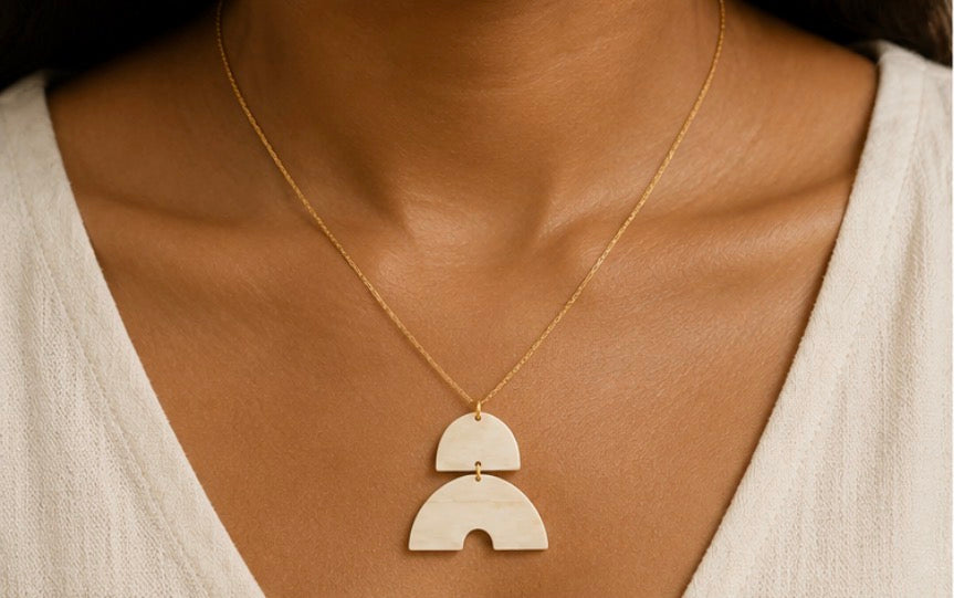 Héritage Arc Necklace — two-piece geometric pendant on a gold-tone chain 